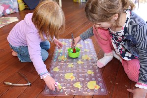 A using her fingers, L using the red tongs