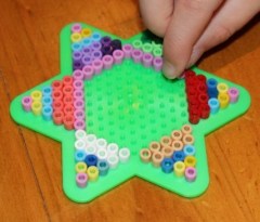 L adding beads to her star peg board.