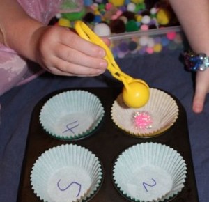 Placing a pom pom into the muffin case.
